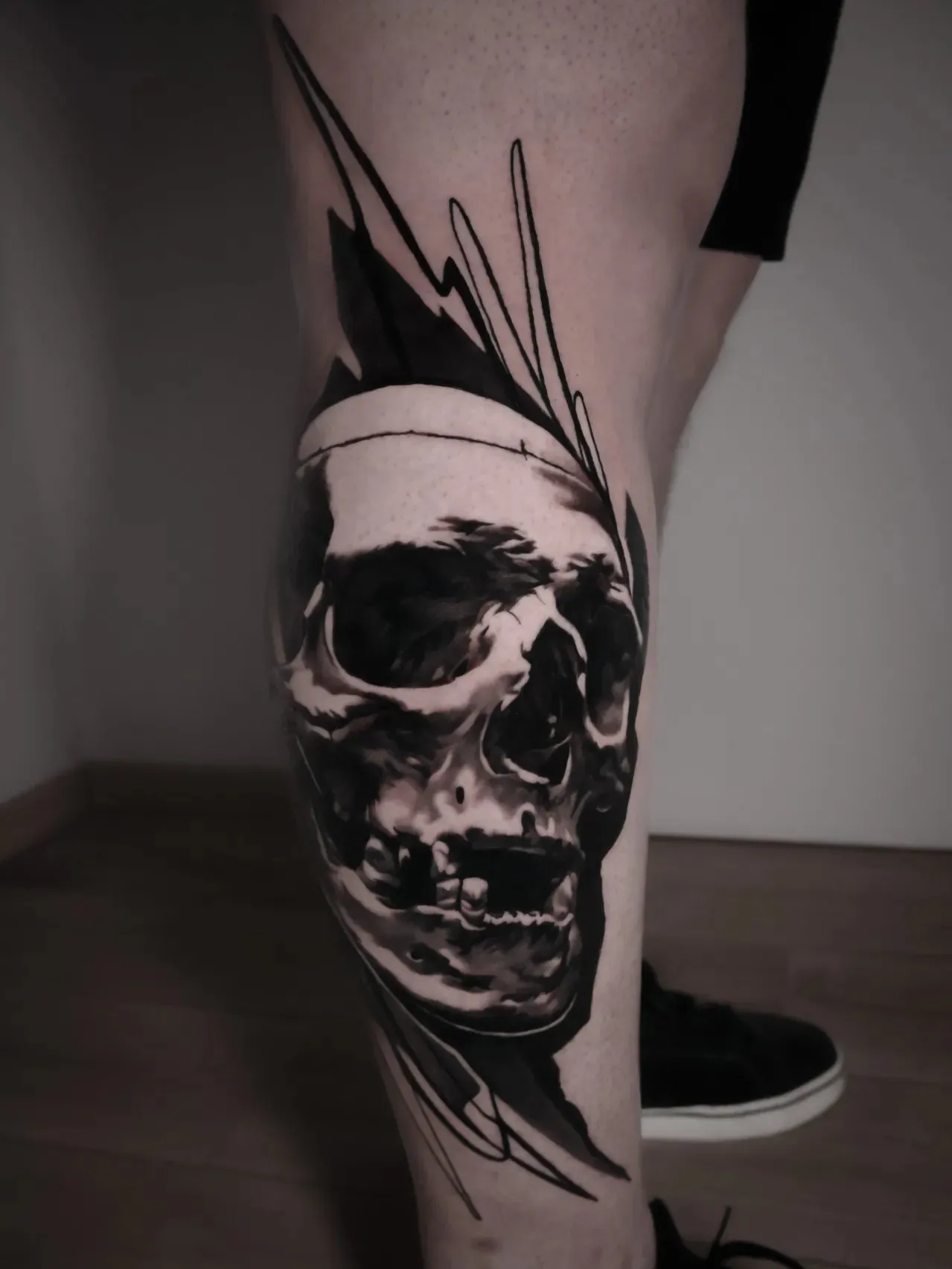 Form in chaos: realistic black and grey skull with sharp black abstract brush strokes, on the calf