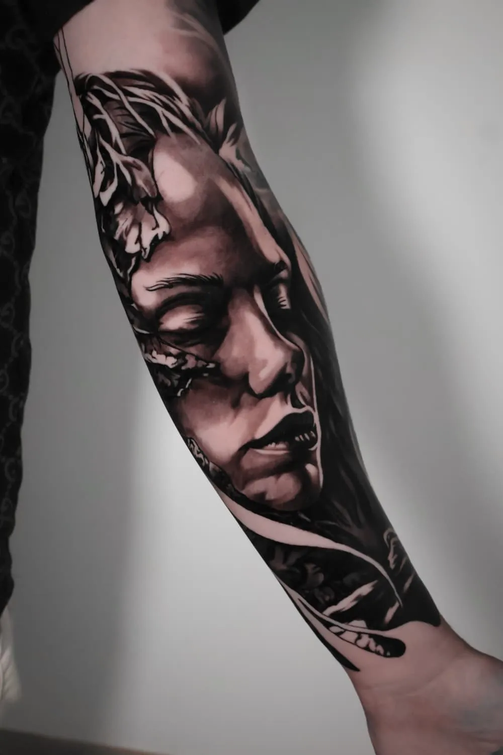 Gesloten ogen: black-and-grey tattoo op de onderarm
