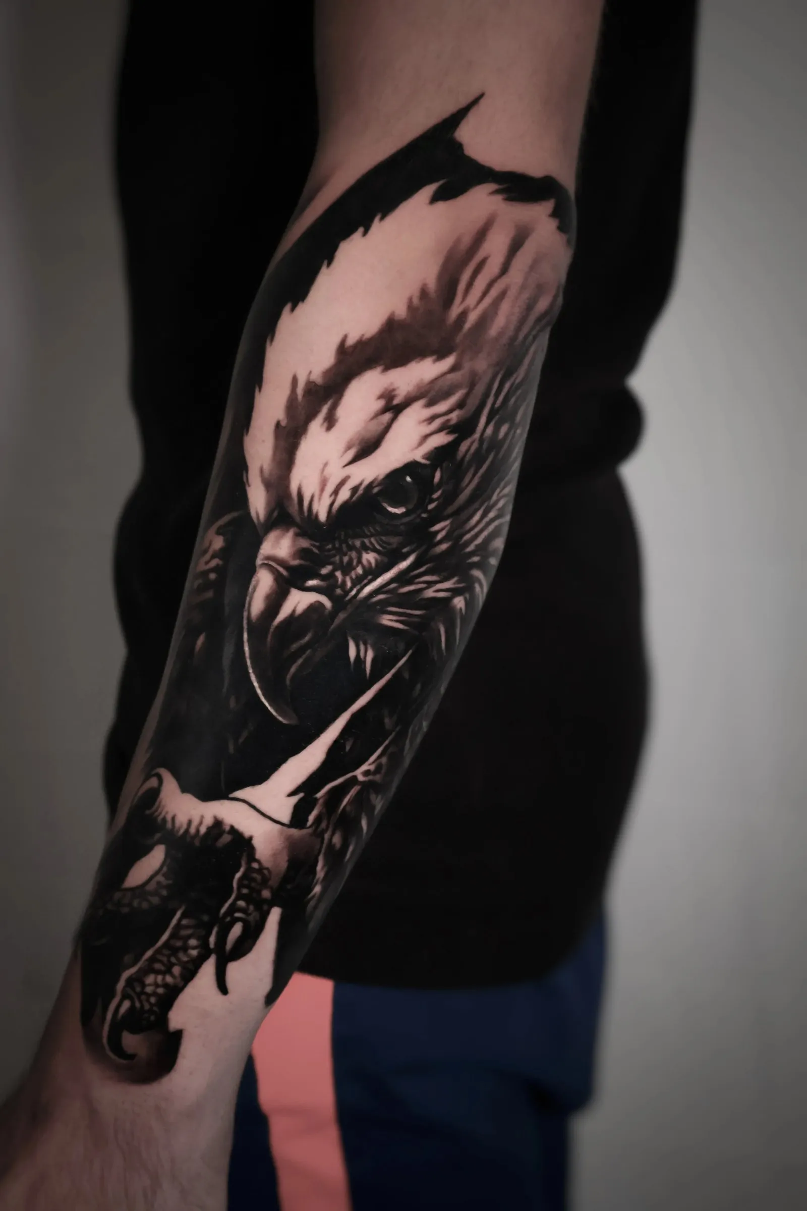 Bound by shades of grey: realistic black and grey eagle with spread feathers, on the forearm