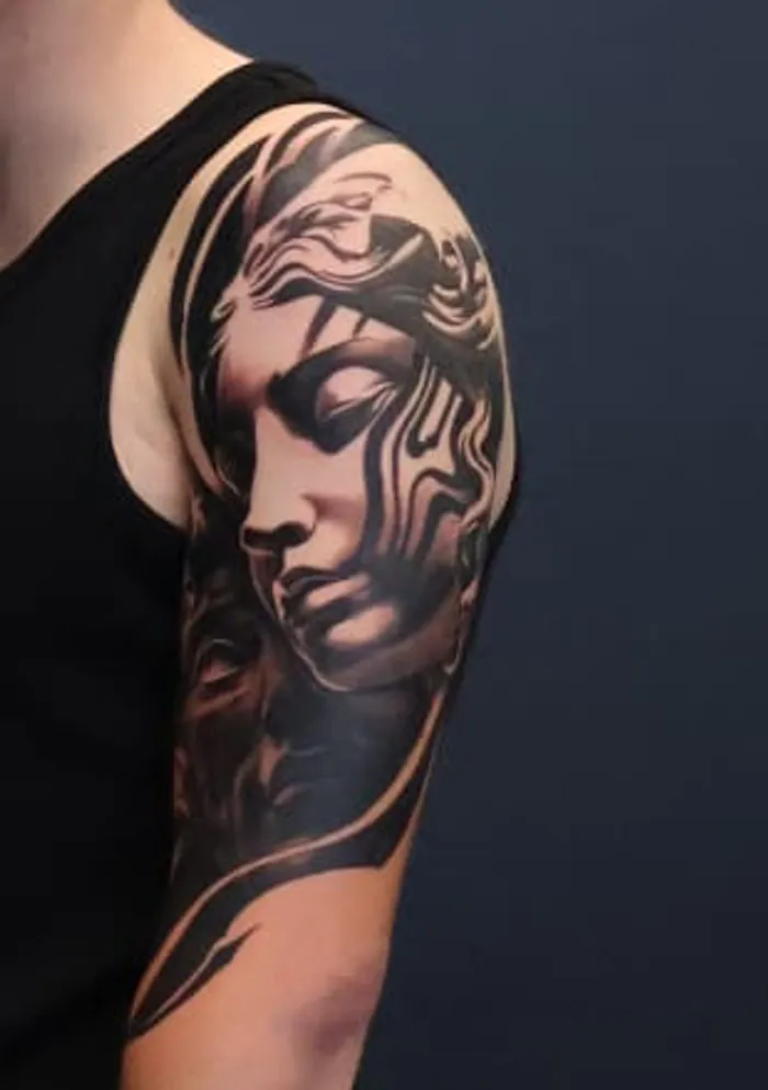 Muze: zwart-grijze tattoo op de schouder en bovenarm